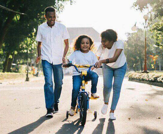 Mother & Father training their daughter to ride a bike.